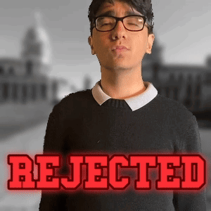 A Man Wearing Glasses Stands In Front Of A Sign That Says Rejected In Red Letters GIF