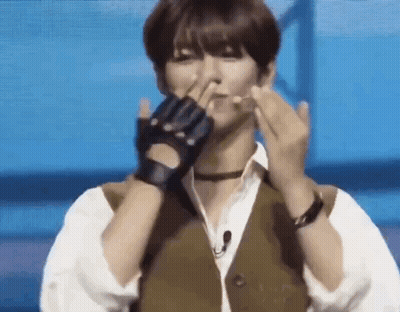 A Man Wearing Gloves And A Vest Is Making A Heart With His Hands . GIF
