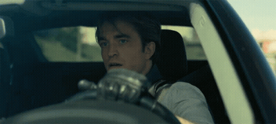 A Man Wearing Gloves Is Driving A Car And Looking Out The Window GIF