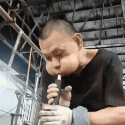 A Man Wearing Gloves Is Smoking A Cigarette In A Factory GIF