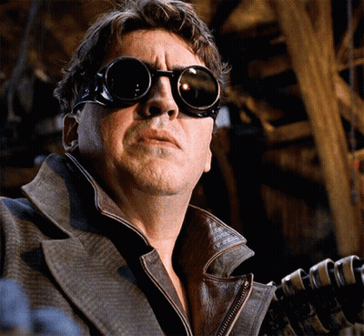 A Man Wearing Goggles And A Leather Jacket Holds A Gun GIF