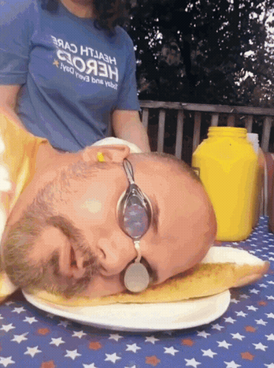 A Man Wearing Goggles Is Laying On A Plate With His Head On A Slice Of Pizza GIF