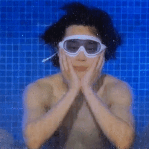 A Man Wearing Goggles Is Swimming In A Blue Pool GIF