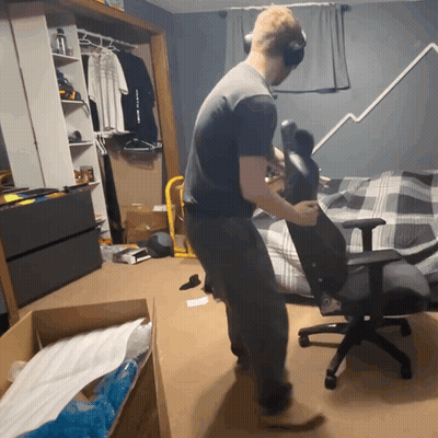 A Man Wearing Headphones Adjusts A Chair In A Room GIF