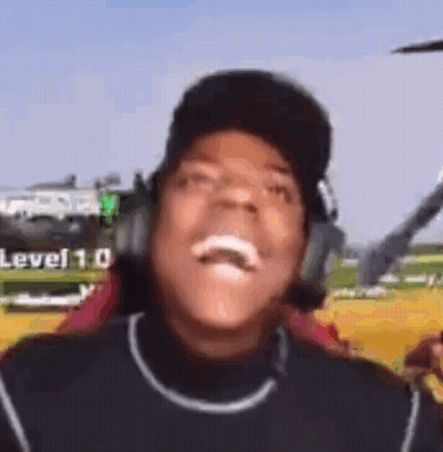 A Man Wearing Headphones And A Baseball Cap Is Laughing In Front Of A Helicopter . GIF