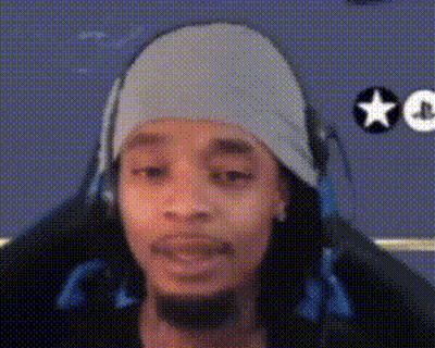 A Man Wearing Headphones And A Beanie Is Sitting In A Chair . GIF