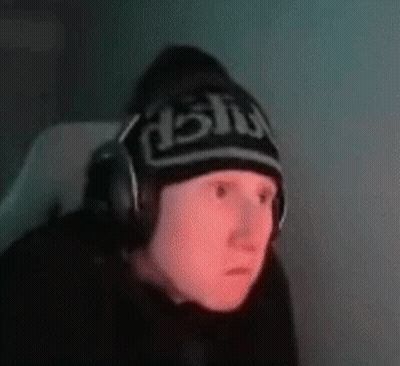 A Man Wearing Headphones And A Beanie Is Sitting In Front Of A Computer . GIF