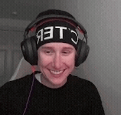 A Man Wearing Headphones And A Beanie Is Smiling And Making A Funny Face . GIF