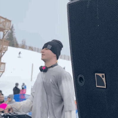 A Man Wearing Headphones And A Beanie Is Standing In Front Of A Speaker GIF