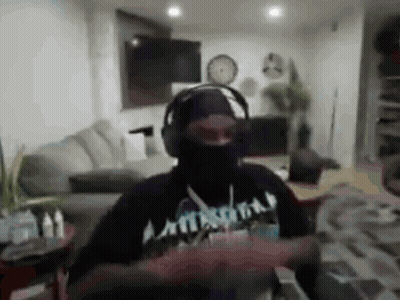 A Man Wearing Headphones And A Black Mask Is Dancing In A Living Room . GIF