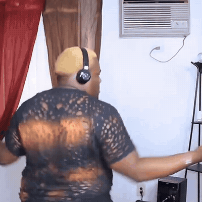 A Man Wearing Headphones And A Black Shirt Is Dancing In A Living Room GIF