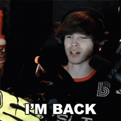 A Man Wearing Headphones And A Black Shirt Is Sitting In Front Of A Microphone And Saying I 'M Back . GIF