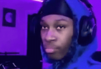 A Man Wearing Headphones And A Blue Hoodie Is Making A Funny Face In A Room With Purple Lights . GIF