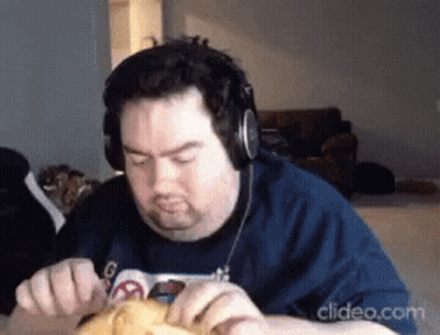 a man wearing headphones and a blue shirt is eating something