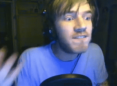 A Man Wearing Headphones And A Blue Shirt Is Looking At The Camera GIF
