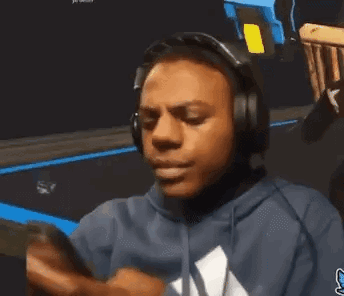 A Man Wearing Headphones And A Blue Sweatshirt Is Looking At His Phone . GIF