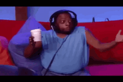 A Man Wearing Headphones And A Blue Tank Top Is Sitting On A Couch Holding A Cup Of Coffee . GIF