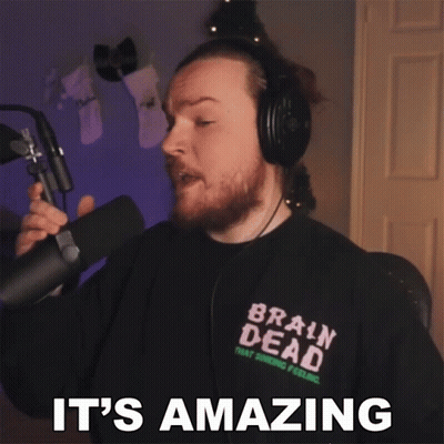 A Man Wearing Headphones And A Brain Dead Shirt Is Holding A Microphone And Says It 'S Amazing GIF