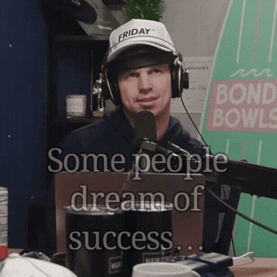 A Man Wearing Headphones And A Friday Hat Is Talking Into A Microphone GIF