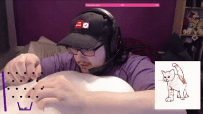 A Man Wearing Headphones And A Hat Is Playing A Game With A Picture Of A Cat Behind Him GIF