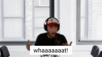 A Man Wearing Headphones And A Hat Is Sitting At A Table With A Sign That Says Whaaaaaat . GIF