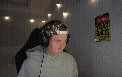 A Man Wearing Headphones And A Hat Is Sitting In Front Of A Computer . GIF