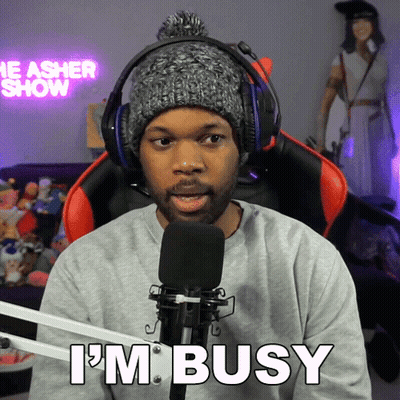 A Man Wearing Headphones And A Hat Says I 'M Busy In Front Of A Microphone GIF