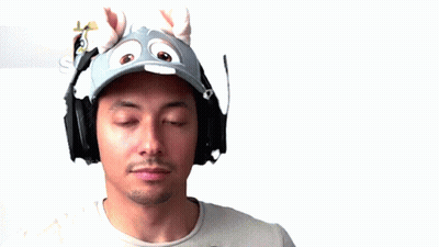 A Man Wearing Headphones And A Hat Sticking His Tongue Out . GIF