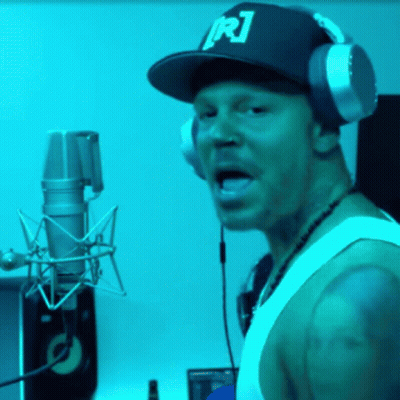 A Man Wearing Headphones And A Hat With R1 On It GIF