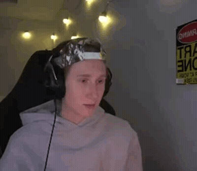 A Man Wearing Headphones And A Hat With Tape On It Is Sitting In Front Of A Sign That Says Danger . GIF