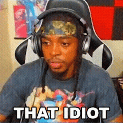 A Man Wearing Headphones And A Headband Is Sitting In A Chair With The Words `` That Idiot '' Written On His Face . GIF