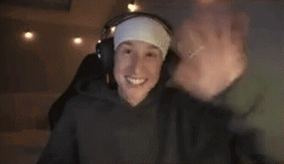 A Man Wearing Headphones And A Headband Is Waving His Hand . GIF