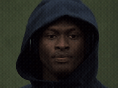 a man wearing headphones and a hooded jacket looks at the camera