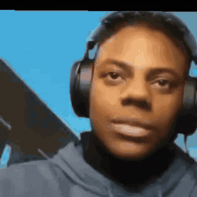 A Man Wearing Headphones And A Hoodie Is Looking At The Camera . GIF