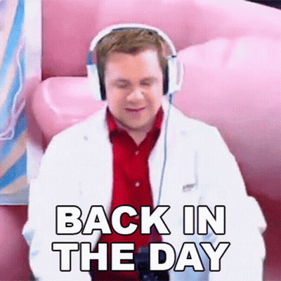 A Man Wearing Headphones And A Lab Coat Is Sitting On A Pink Couch And Saying `` Back In The Day '' . GIF