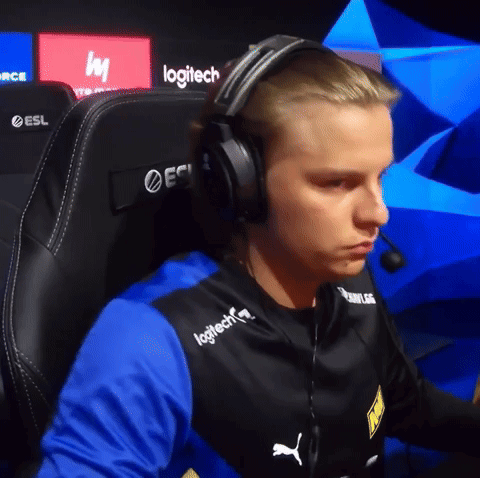 A Man Wearing Headphones And A Logitech Shirt Sits In A Gaming Chair GIF