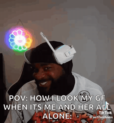 A Man Wearing Headphones And A Mask Is Sitting In Front Of A Colorful Light . GIF