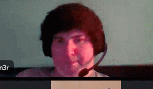 A Man Wearing Headphones And A Microphone Is Sitting In Front Of A Computer Screen . GIF