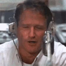 A Man Wearing Headphones And A Microphone Is Talking Into A Microphone . GIF