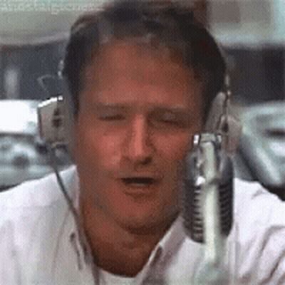 A Man Wearing Headphones And A Microphone Is Talking Into A Microphone . GIF