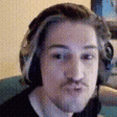 A Man Wearing Headphones And A Mustache Is Making A Funny Face . GIF