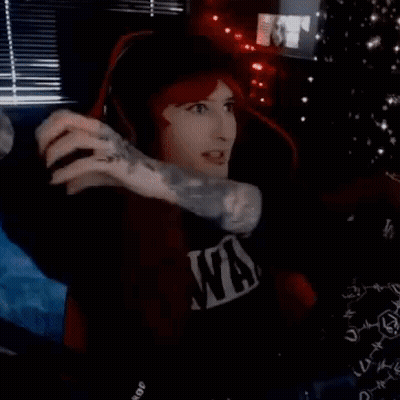 A Man Wearing Headphones And A Nirvana Shirt Is Sitting In A Dark Room . GIF