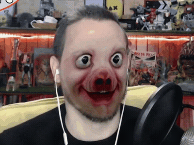 A Man Wearing Headphones And A Pig Mask Looks At The Camera With A Sign In The Background That Says Iron Pier GIF