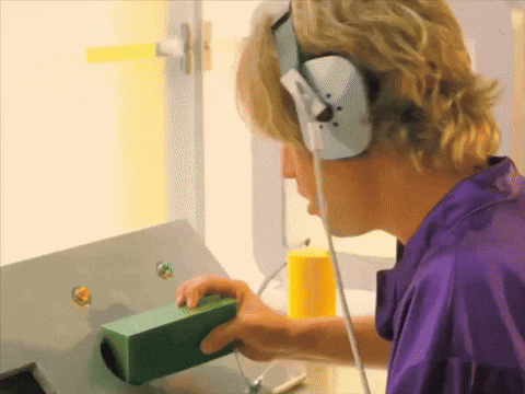 A Man Wearing Headphones And A Purple Shirt Is Holding A Green Box GIF