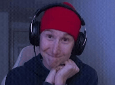 A Man Wearing Headphones And A Red Beanie Smiles GIF