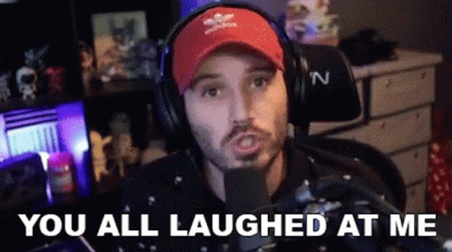 A Man Wearing Headphones And A Red Hat Is Sitting In Front Of A Microphone And Laughing . GIF