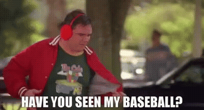 A Man Wearing Headphones And A Red Jacket Is Standing In Front Of A Car And Asking If He Has Seen His Baseball . GIF