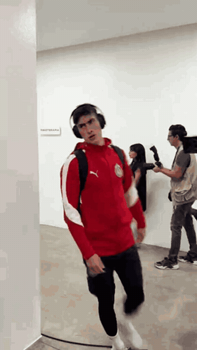 A Man Wearing Headphones And A Red Puma Jacket GIF
