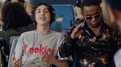 A Man Wearing Headphones And A Shirt That Says Cookies Is Sitting Next To Another Man GIF