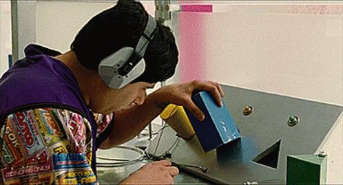 A Man Wearing Headphones And A Shirt That Says Monopoly Is Working On A Machine GIF
